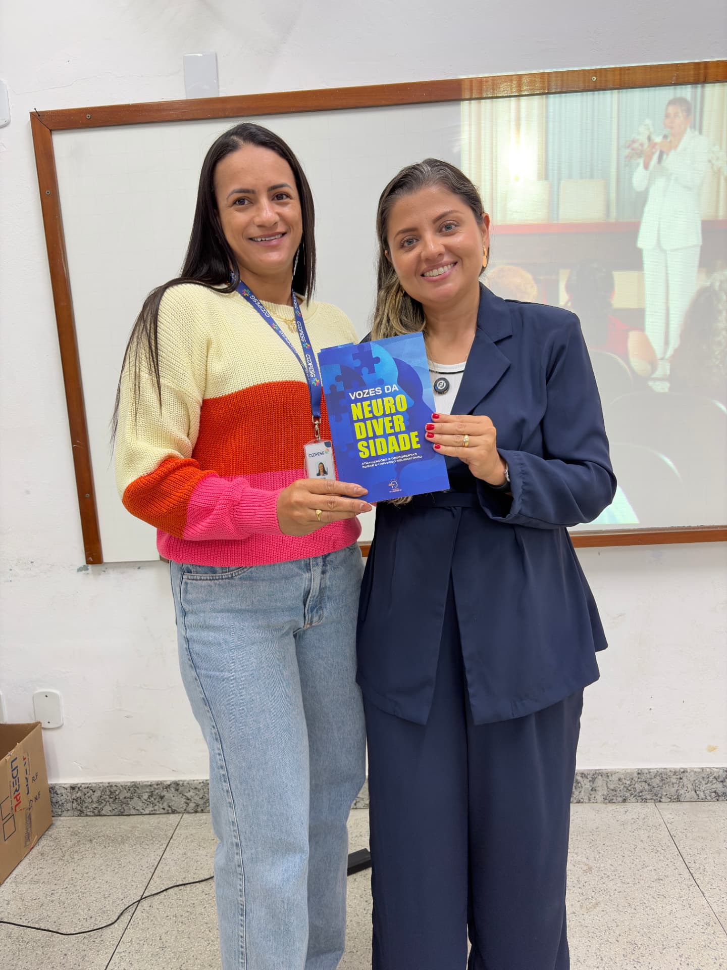 Jéssica Pelissari entrega o livro Vozes da Neurodiversidade a uma profissional da COOPESG