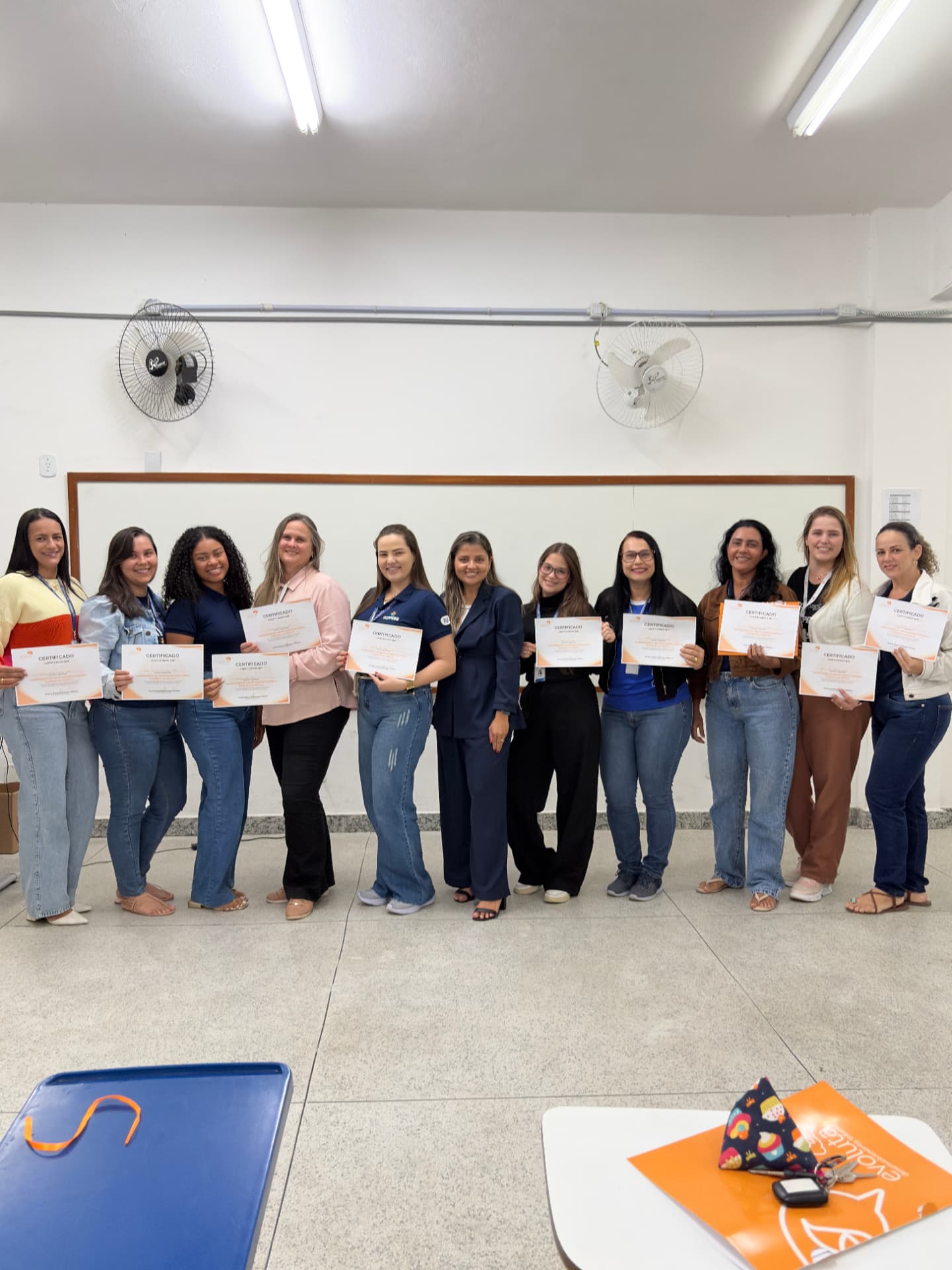 Jéssica Pelissari ao lado das auxiliares e cuidadoras da COOPESG com os certificados da capacitação